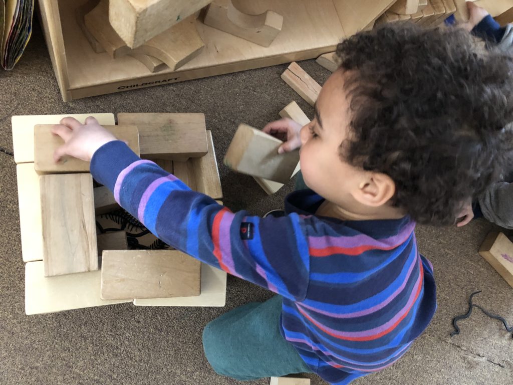 Toddler plays with building block in the classroom at SHED