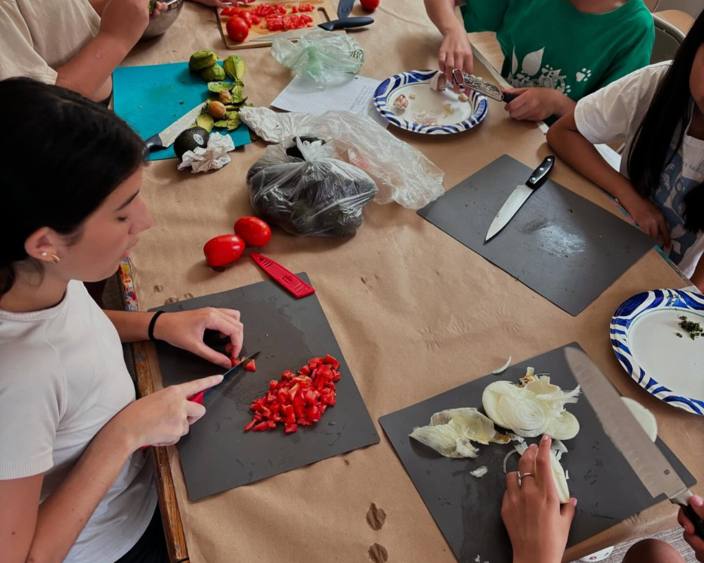 Children chopping vegetables together at a table